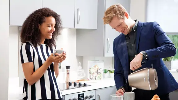 Man And Woman In Kitchen Drinking Hot Drinks