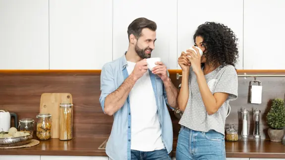 Man And Woman In Kitchen Drinking Hot Drinks