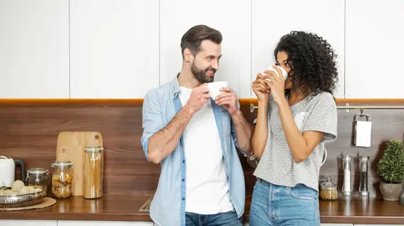 Man And Woman In Kitchen Drinking Hot Drinks