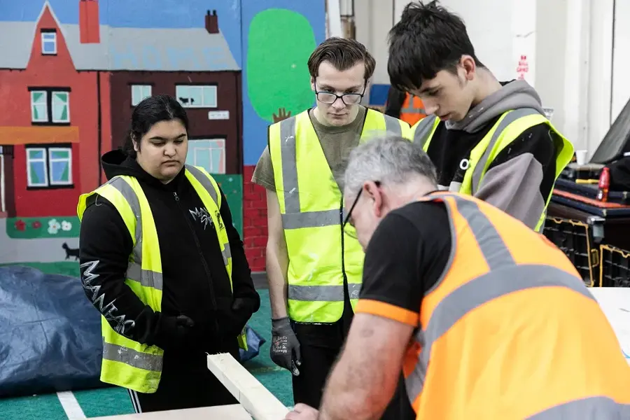 Teens Watch A Demonstration Of Cutting Timber