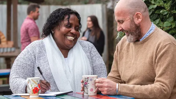 Man And Woman Sat At Table Laughing