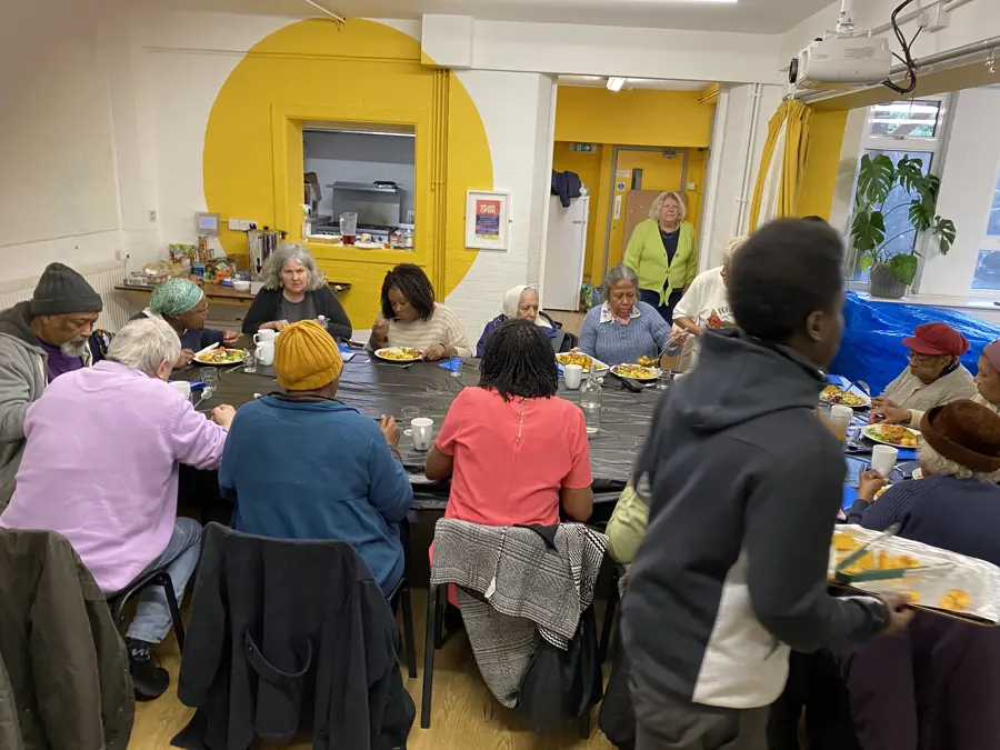 Group Of People Sat At Table Eating